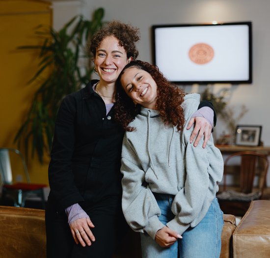 Two people are in a cafe, smiling and hugging